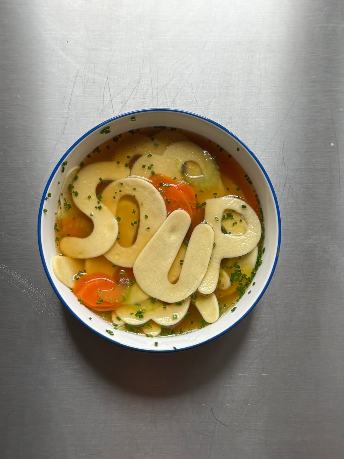 Food art: bowl of soup with dough letters spelling SOUP, top view